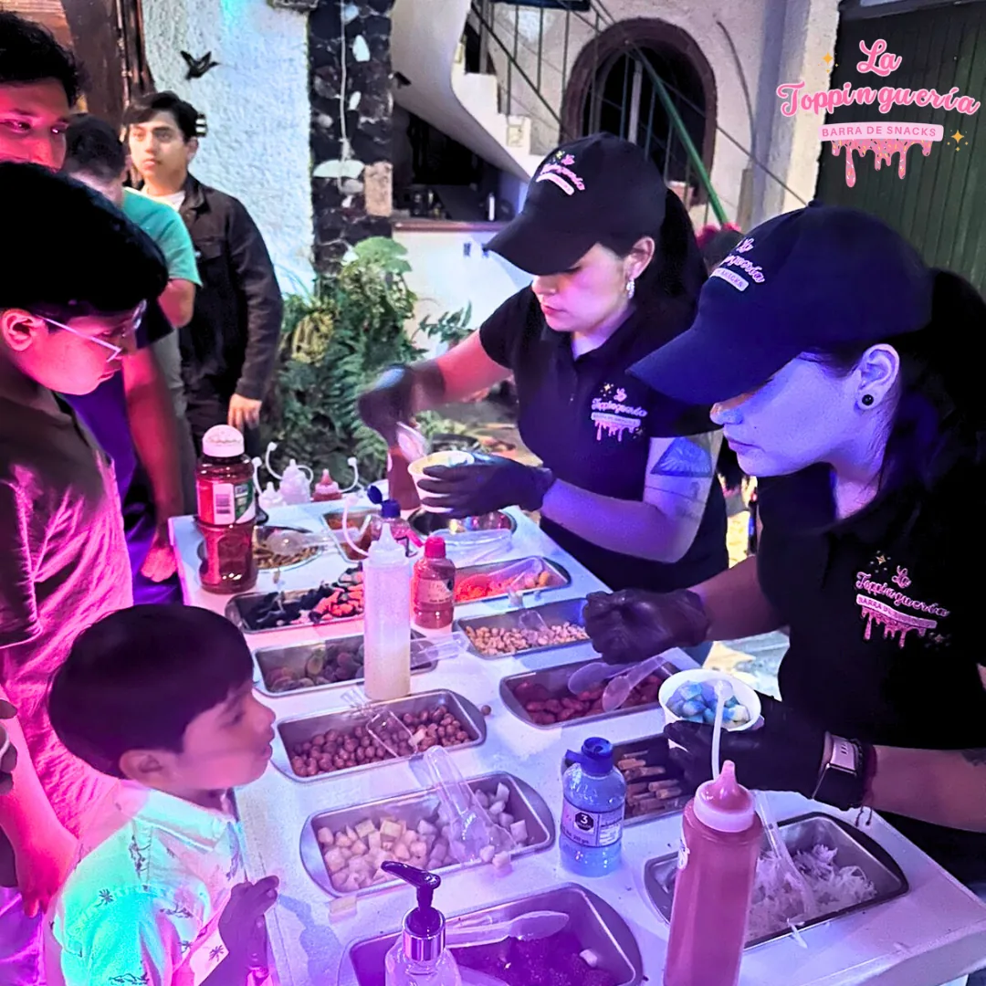 Invitados eligiendo botanas en una fiesta con luces